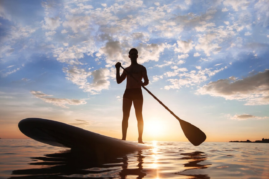 Homme sur Paddle au coucher du soleil